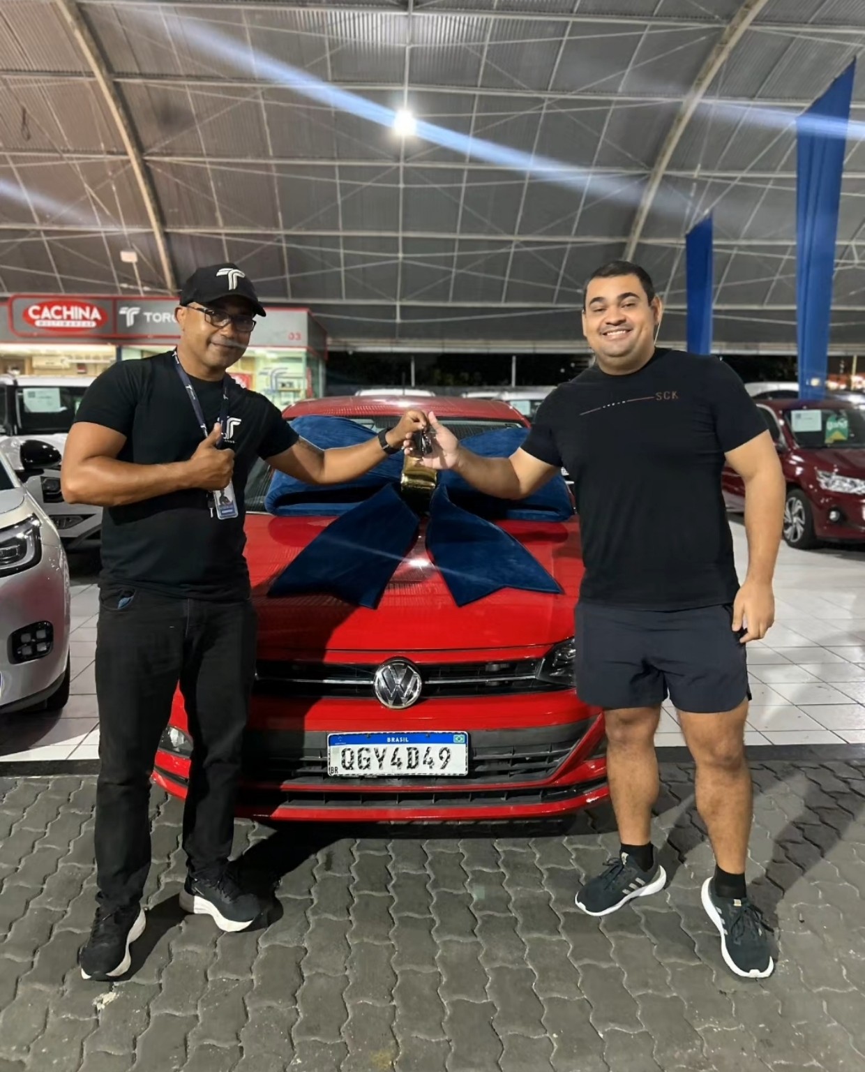 Cliente recebendo as chaves de um carro vermelho